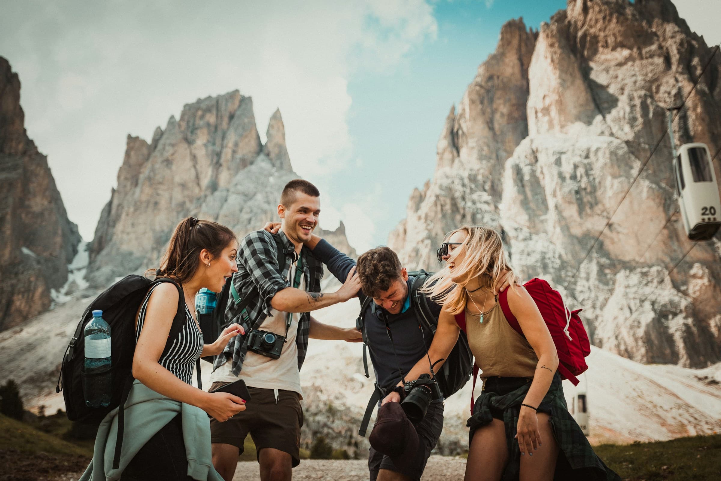 Four friends laughing together on a mountain hike beneath rocky peaks - Adventure Escapes