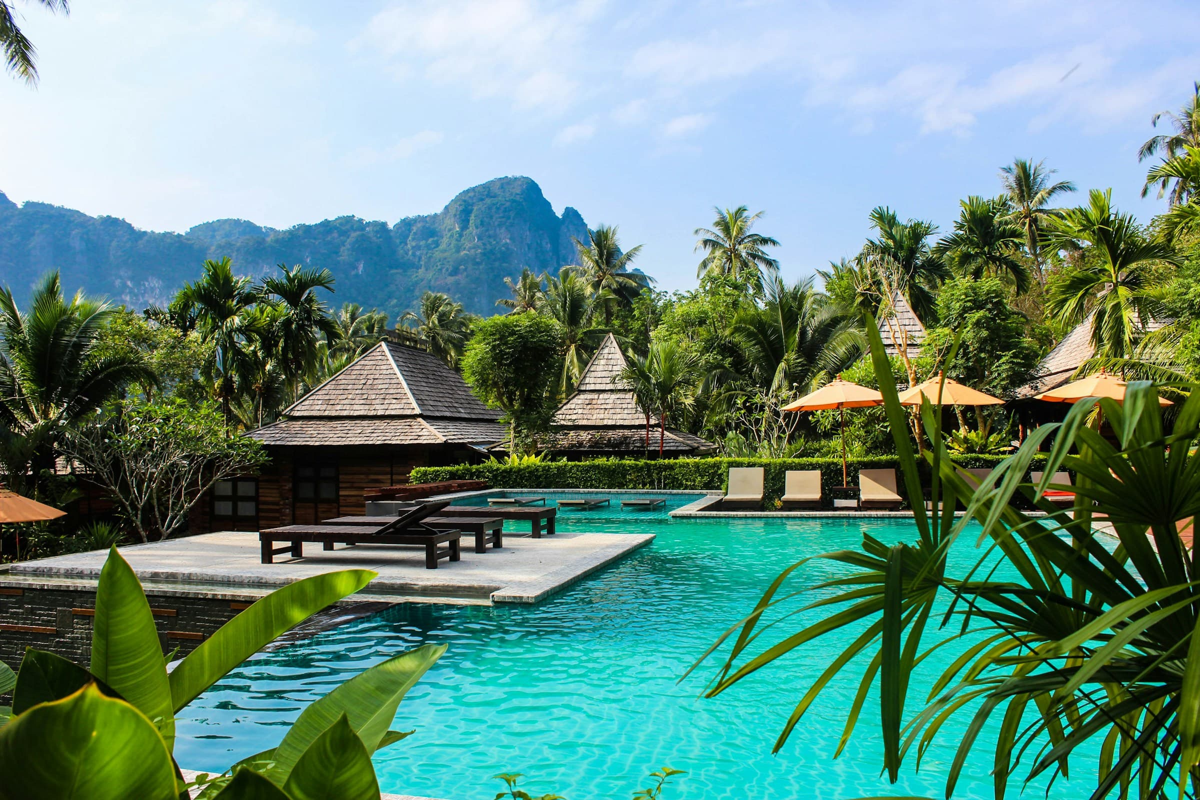 Tropical resort pool beneath green mountains - Coastal Retreats