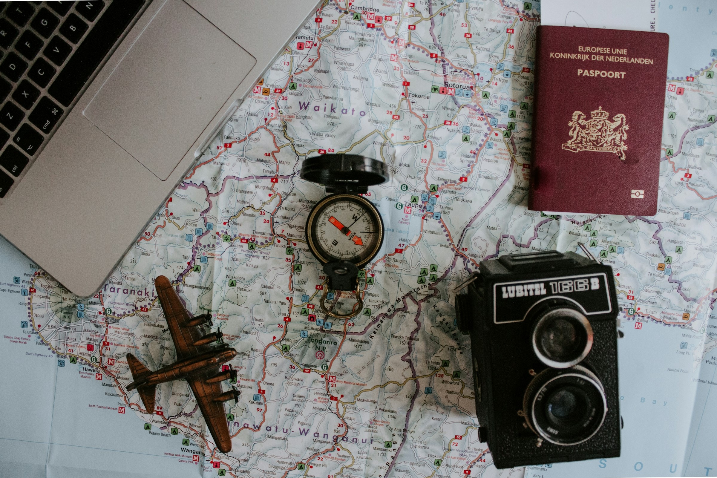 A travel map with a compass, passport, vintage camera and model aeroplane